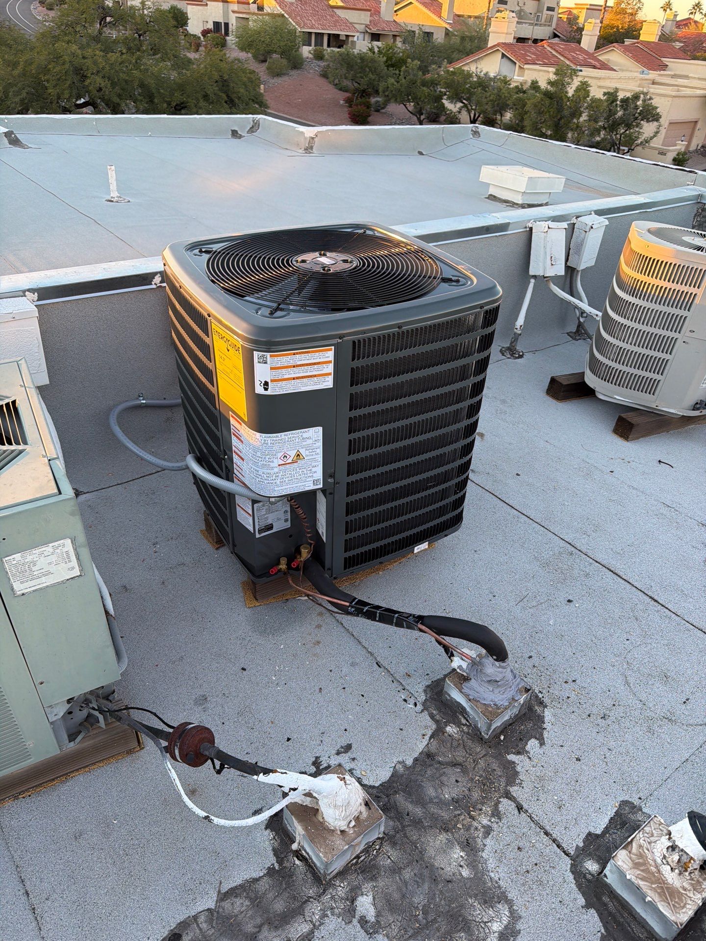 A black condenser unit installed on a flat rooftop