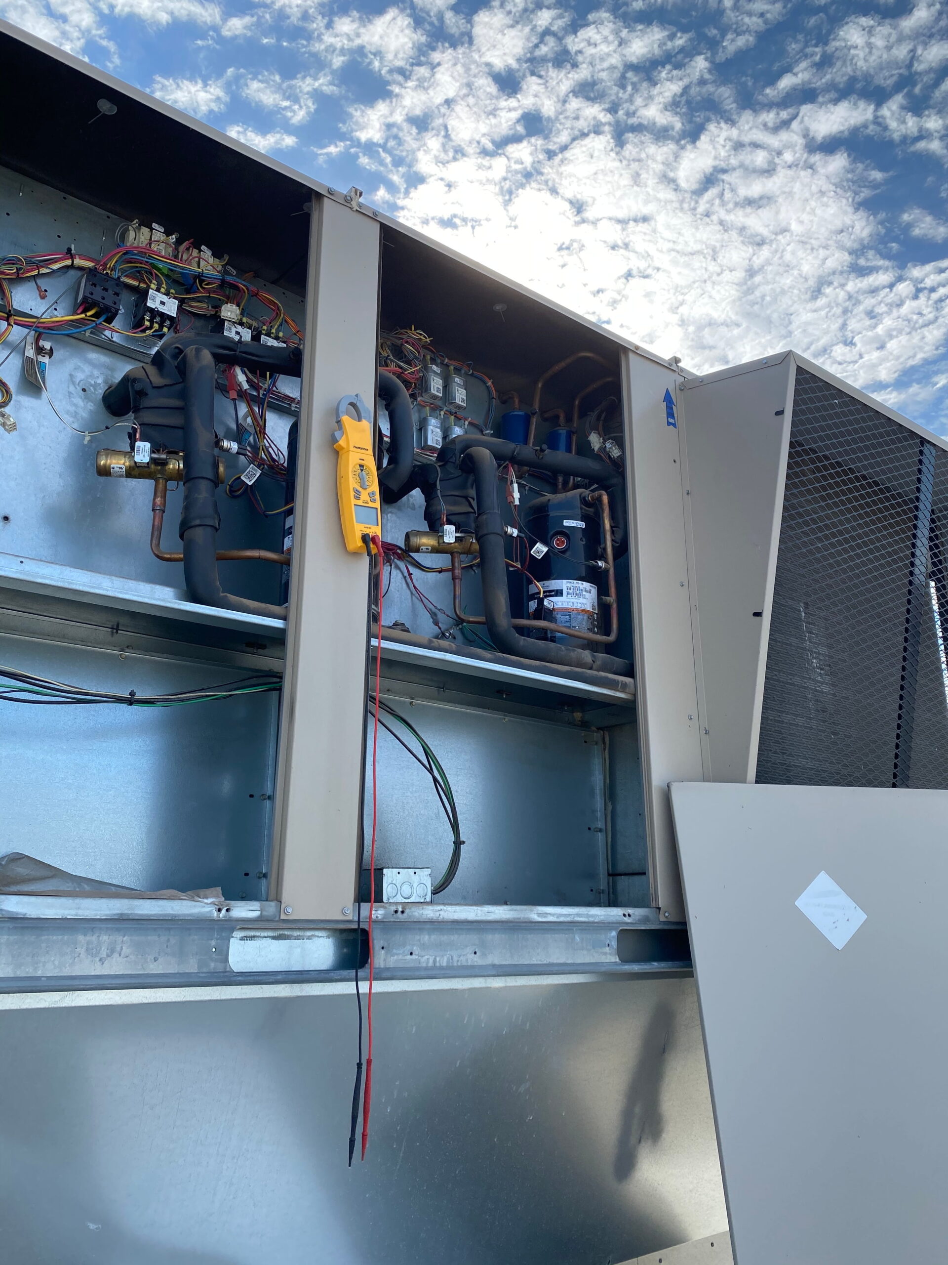 A large commercial HVAC unit opened for service under a blue sky