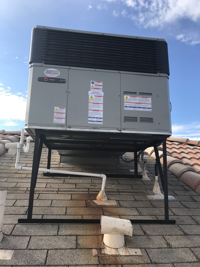 A packaged HVAC system mounted on a stand on a tile roof