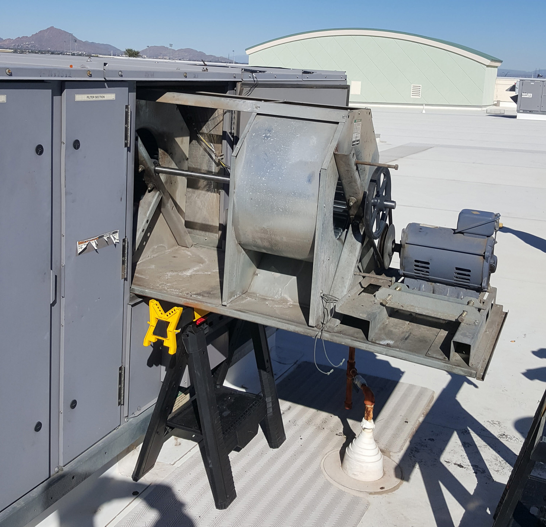 An open rooftop HVAC unit with its blower assembly exposed during service