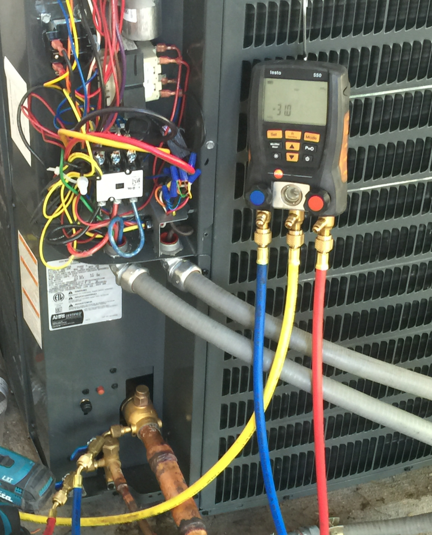 A digital manifold gauge set connected to a condenser during maintenance