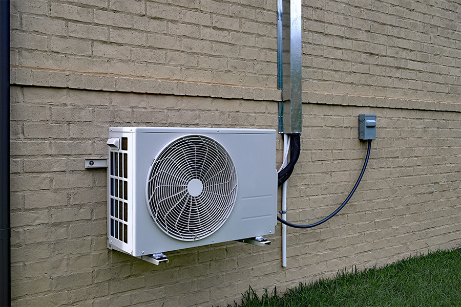 A mini split outdoor unit mounted on a brick wall